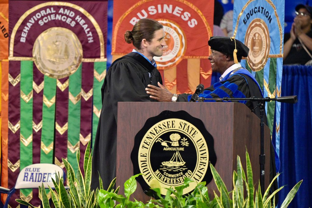 Andrew Forsthoefel, left, is welcomed to the platform by MTSU President Sidney A. McPhee Aug. 21 at the 2022 University Convocation at Murphy Center. Forsthoefel, author of "Walking to Listen," delivered the main address. (MTSU photo by Andy Heidt)