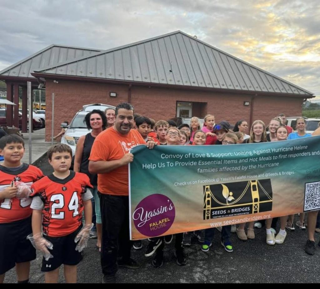 Yassin Syrian, owner of Yassin's Falafel Hous, holds a sign as his team brings in truckloads of donations from Knoxville and food to cook hot meals on site in Greenville, Tenn. (Photo submitted)