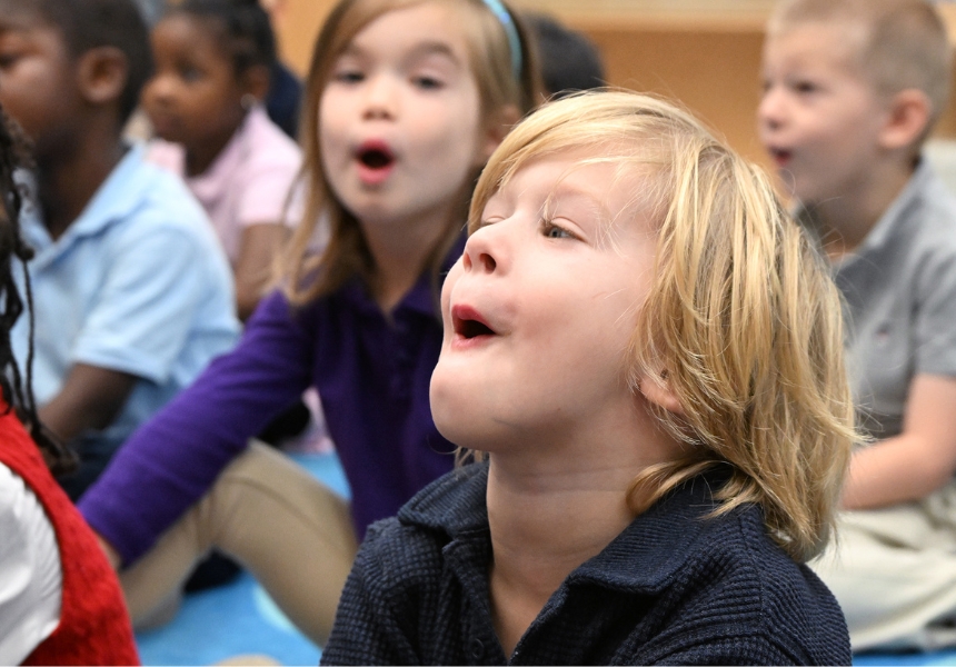 preschool boy and classmates sitting on class mat laughing