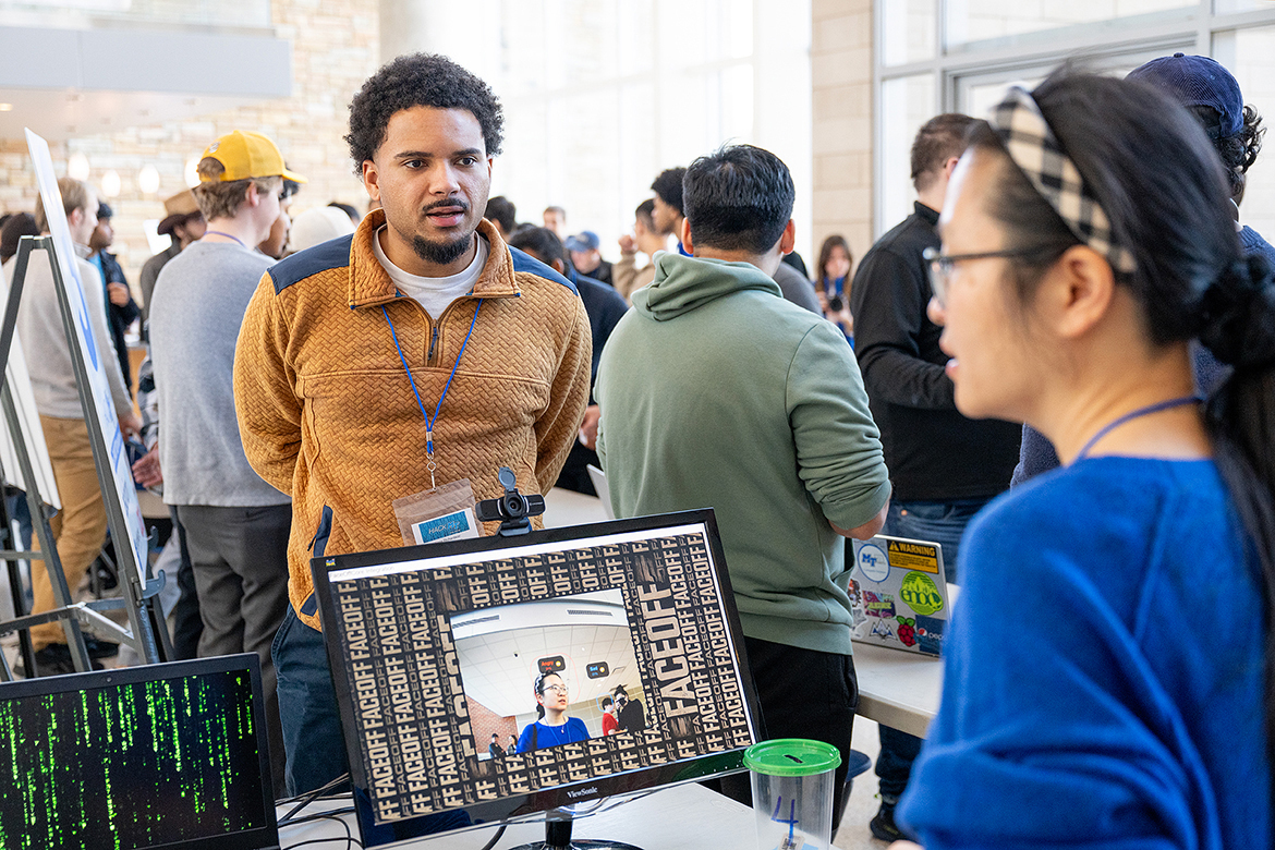 Kane Richardson, left, a software engineer with Nashville, Tenn.-based LRQ and a mentor for the “FaceOff” team competing in the 10th annual Middle Tennessee State University Computer Science Department HackMT, explains the web app process that tracks facial emotions and displays them on a laptop screen to MTSU computer science assistant professor Xin Yang in the Science Building on campus in Murfreesboro, Tenn., on Sunday, Feb. 2. Judges awarded Richardson’s team first place. (MTSU photo by Cat Curtis Murphy)