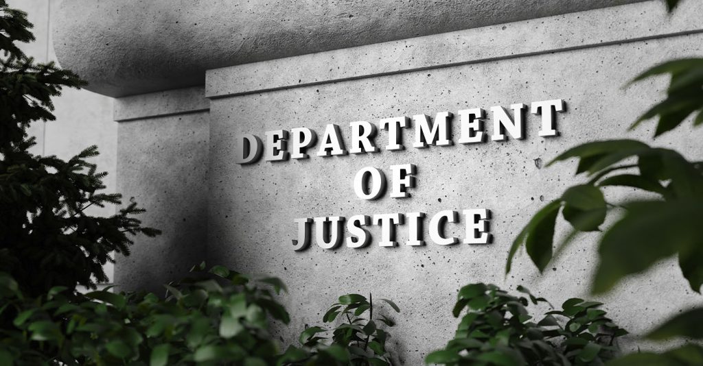 Silver sign of Department of Justice on a classical concrete wall with plants as foreground. Illustration of the concept of enforcement of federal laws