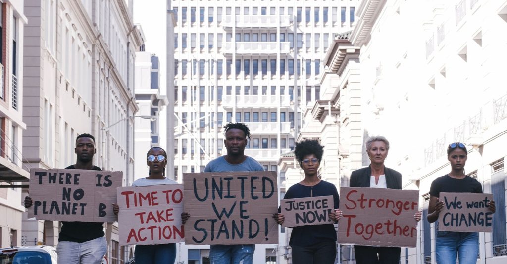 Protest group activism, justice portrait and change in street with poster in hands. Crowd people writing, city sign for solidarity peace or diversity of race, religion and community in metro together (Photo by Armand Burger)