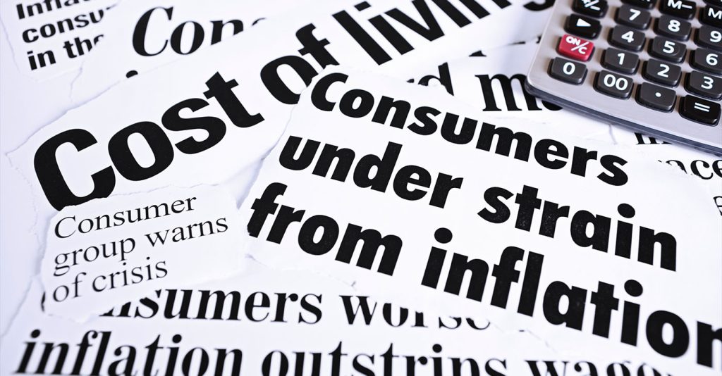 Calculator on newspaper headlines about cost of living and inflation