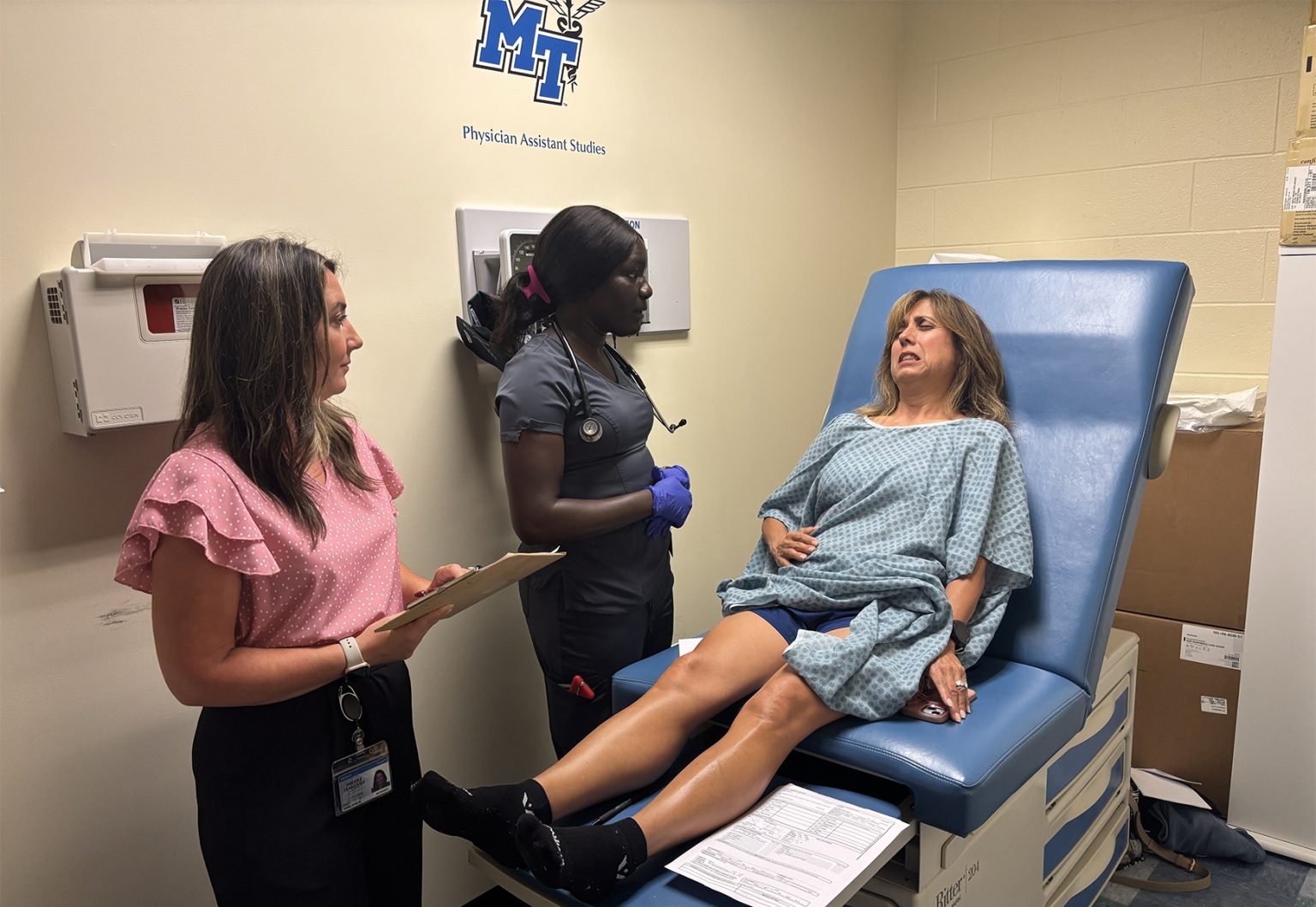 Ashley Bjork, left, a clinical associate professor in the Physician Assistant Studies program at Middle Tennessee State University in Murfreesboro, Tenn., accompanies first-year student Nayatuil “Twilly” Tongyik, of Gallatin, Tenn., to examine a patient-actor during a mock mass casualty simulation held in July inside the Cason-Kennedy Nursing Building. Tongyik diagnosed the patient-actor with bleeding in the abdomen — the correct assessment. (MTSU photo by Nancy DeGennaro)