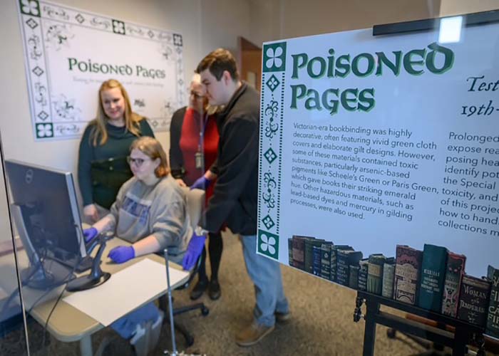 MTSU students uncover hidden hazards in historic Victorian-era books in Special Collections Chemistry instructor Sarah Pierce, standing at left, Special Collections librarian Susan Martin, center, and chemistry graduate student Ethan Coyle look over the shoulders of forensic science student Brittney Cupp as they examine incoming data from the X-ray fluorescence spectroscopy, or XRF, set up in the Special Collections at Middle Tennessee State University’s James E. Walker Library in Murfreesboro, Tenn. The machine is used to identify and quantify toxic compounds and heavy metals found in the pigments used in many 19th-century books housed in the university’s Special Collections. The “Poisoned Pages” project was made possible through a University Research and Creative Activity, or URECA, grant that bolstered the collaboration between the Department of Chemistry and the library. (MTSU photo by J. Intintoli)